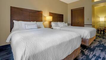 Habitación de hotel con dos camas, cabecero de madera, lámpara y piso alfombrado.