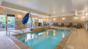 An indoor swimming pool with a lifeguard on duty sign, a blue lifeguard chair, and a 3 FT no diving sign.