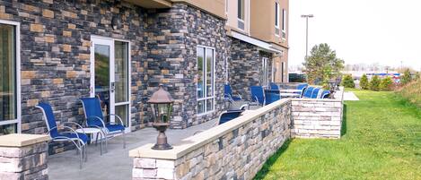 A building with a stone facade, outdoor seating area with chairs, and a lamp post.