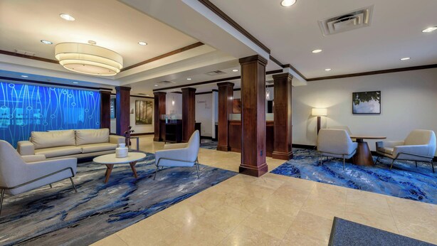 A spacious lobby with a modern design, featuring a large seating area with a sofa and chairs, a coffee table, and a decorative rug.