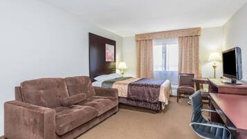 A hotel room with a bed, a sofa, a desk, a chair, a television, and a lamp.