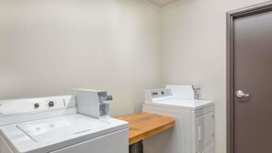 Una sala de bugaderia amb dues màquines de rentar, una màquina d'assecar i una banca de fusta.