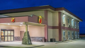 Un hotel amb el rètol de Super 8, un piló de pedra i una entrada coberta.
