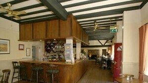 A bar area with wooden beams, a counter, and stools. There are tables and chairs in the background. - The Bolingbroke Hotel (Swindon)