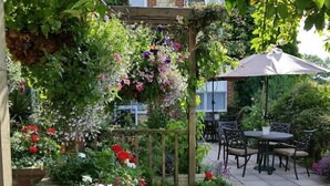 A garden with a wooden pergola, various flowering plants, and outdoor furniture. - The Bolingbroke Hotel (Swindon)