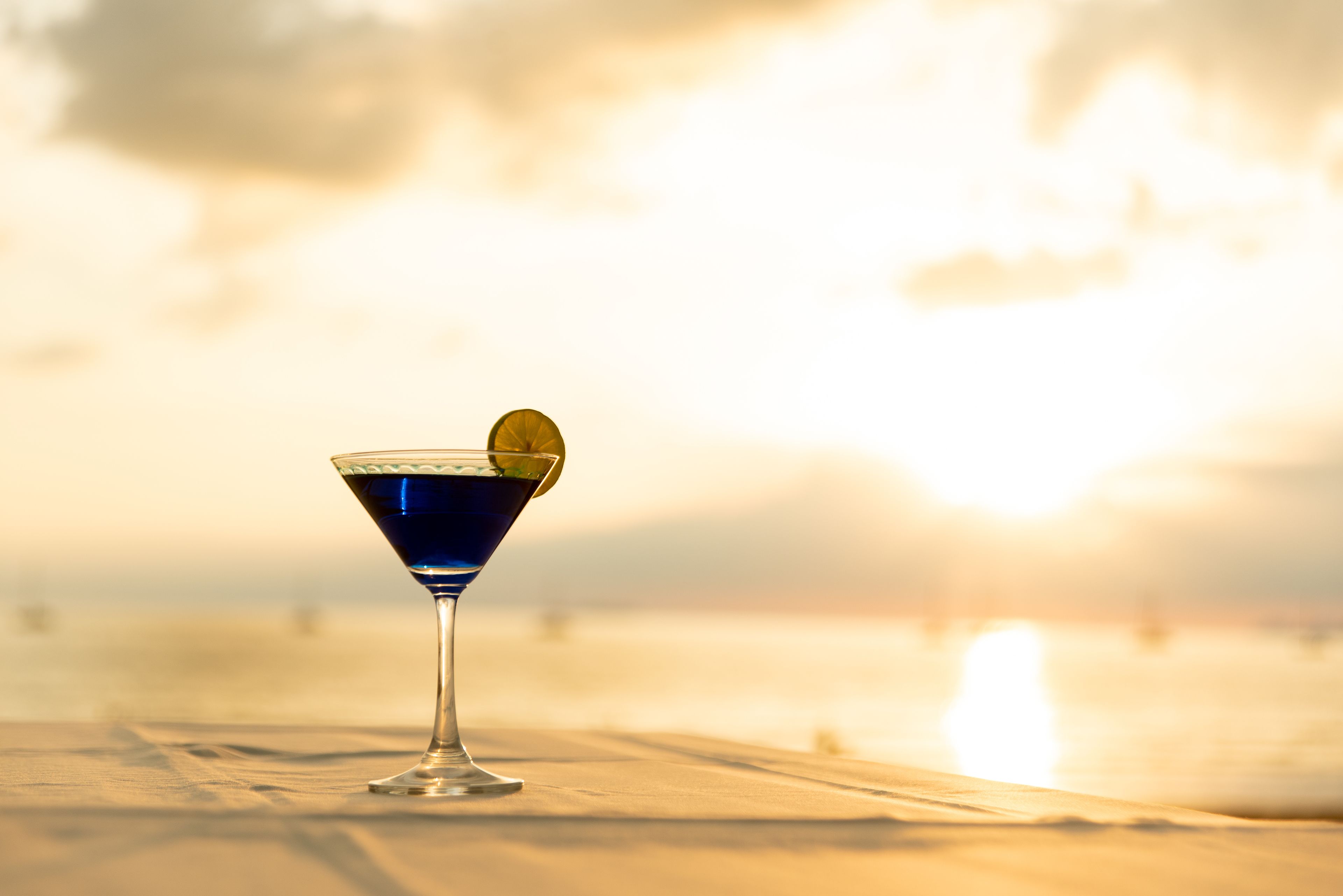 A martini glass with a lime garnish on a wooden surface.