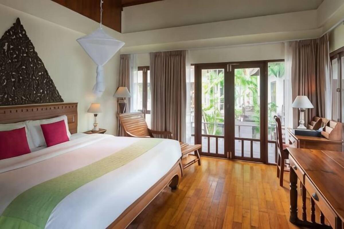 A hotel room with a bed, a desk, a chair, and a view of the outdoors.
