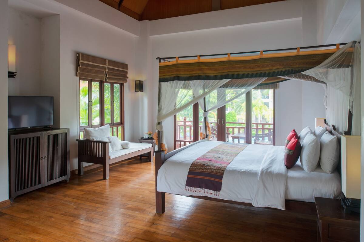 A spacious bedroom with a large bed, a television, and a wooden cabinet.