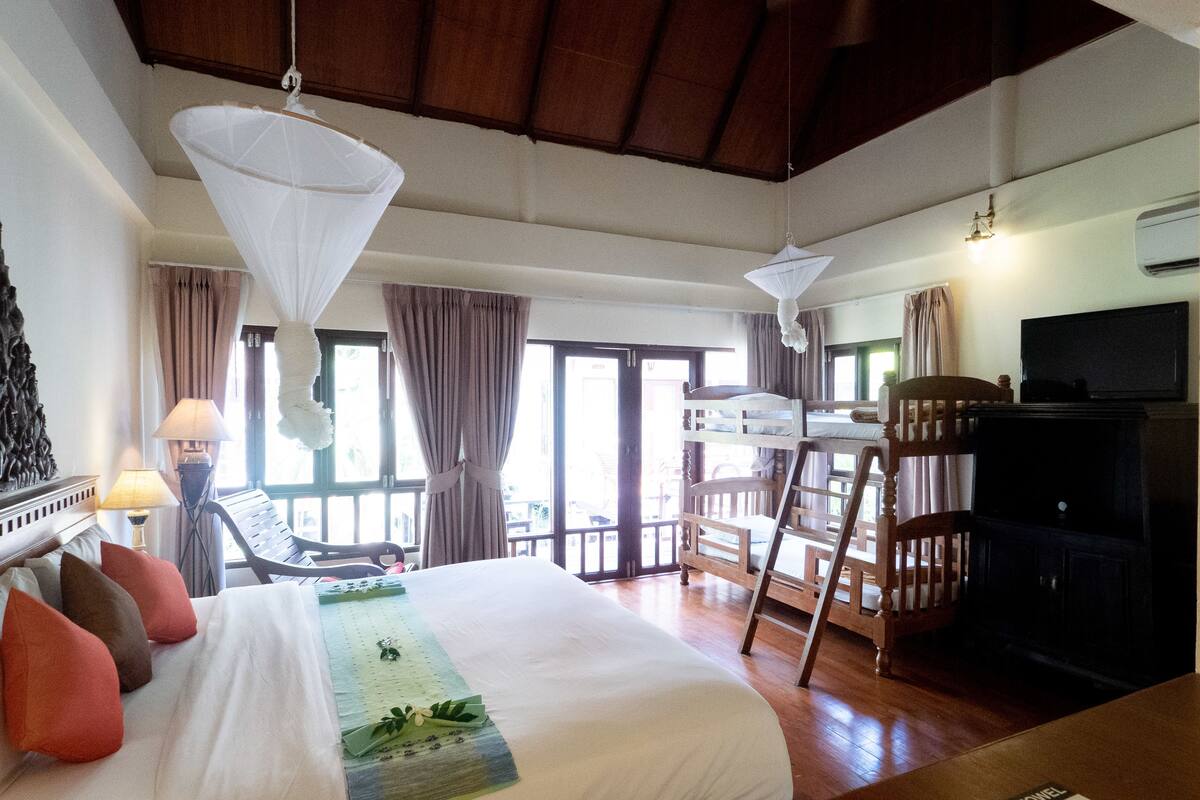 A hotel room with a bed, a chair, a TV, and a balcony.