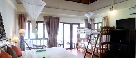 Una habitación de hotel con cama, una silla, televisor y balcón.