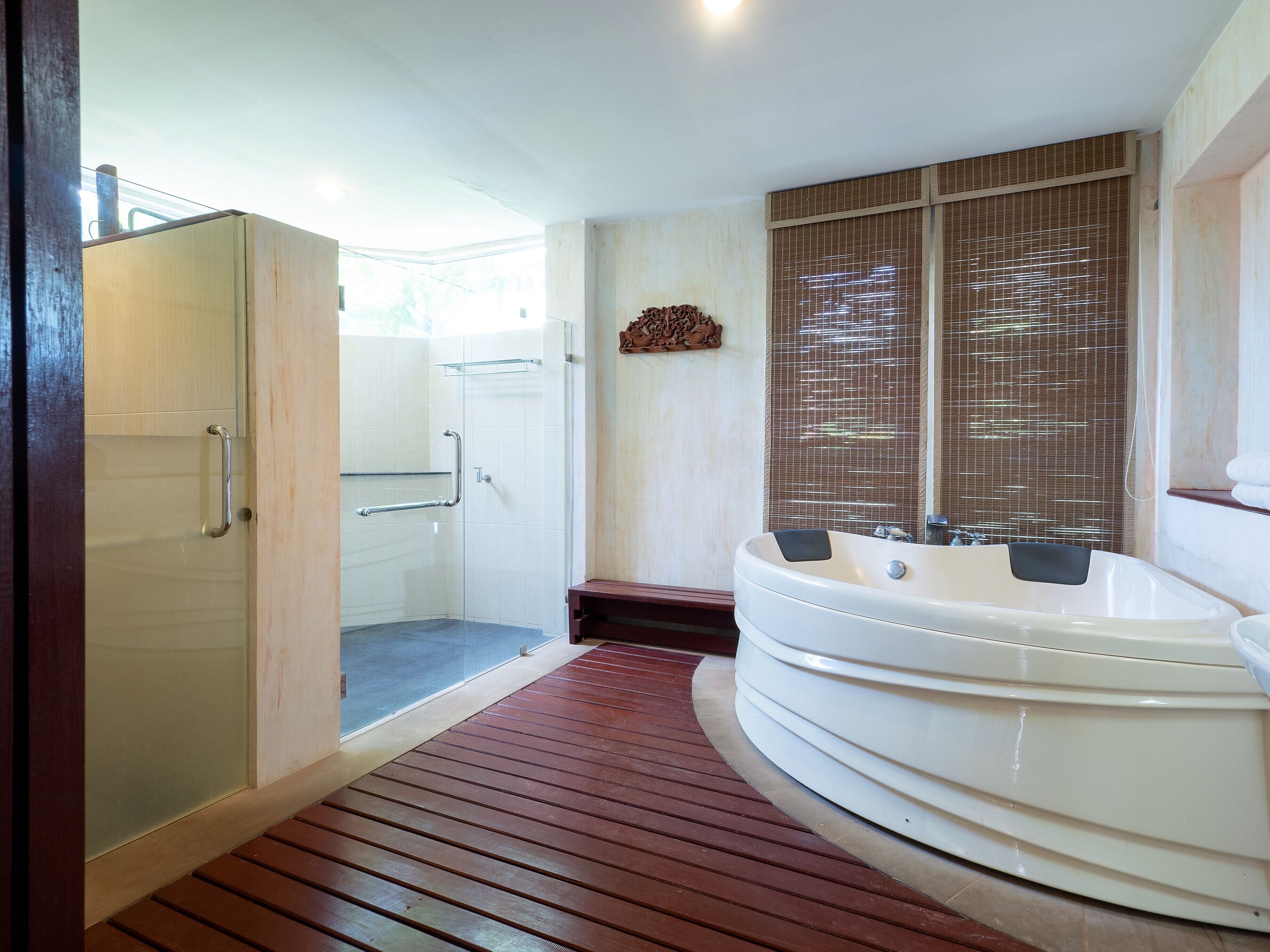 Un baño moderno con cabina de ducha, suelo de madera y una bañera grande.