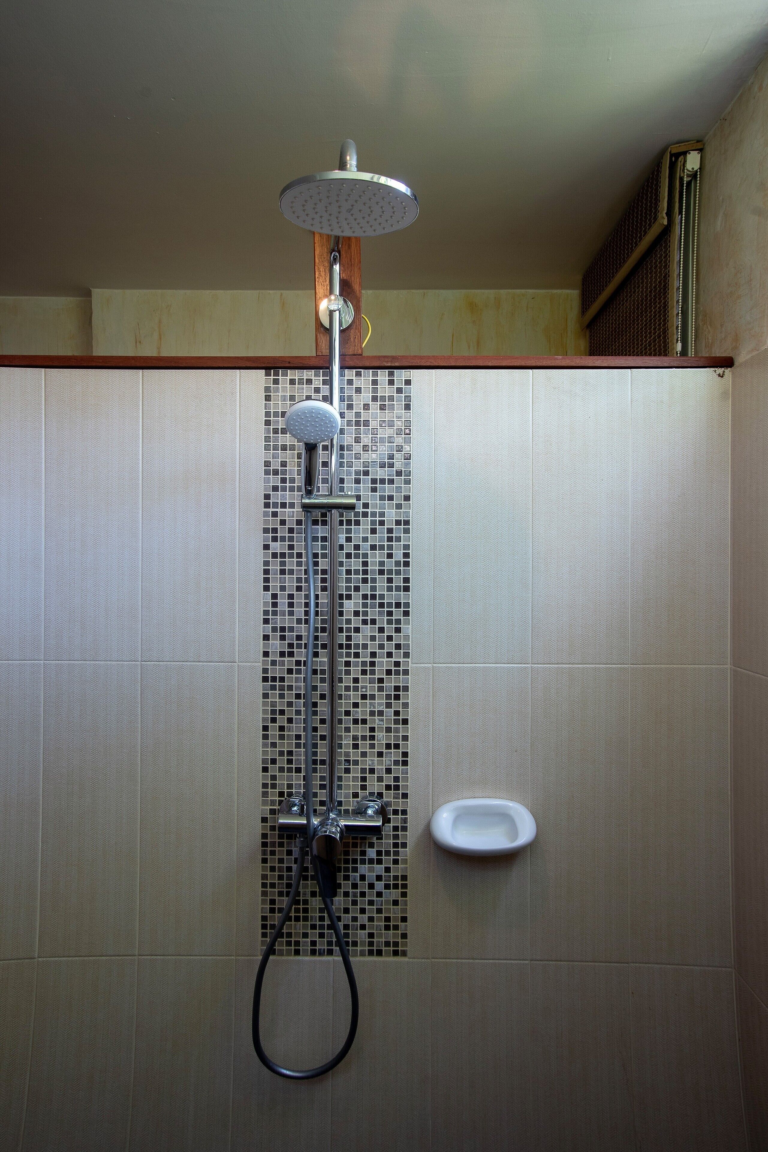 A shower with a rain showerhead, a handheld showerhead, and a handheld shower hose.
