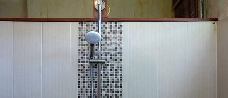 A shower with a rain showerhead, a handheld showerhead, and a handheld shower hose.
