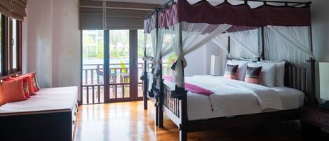 A bedroom with a four-poster bed, a daybed, and a view of the outdoors.