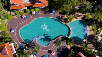 Relax by the infinity pool surrounded by palm trees and shaded seating areas.