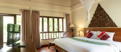 A hotel room with a bed, a desk, a television, and a window with curtains.