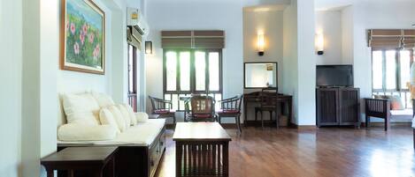 A spacious living area with a sofa, chairs, a wooden coffee table, and a TV.