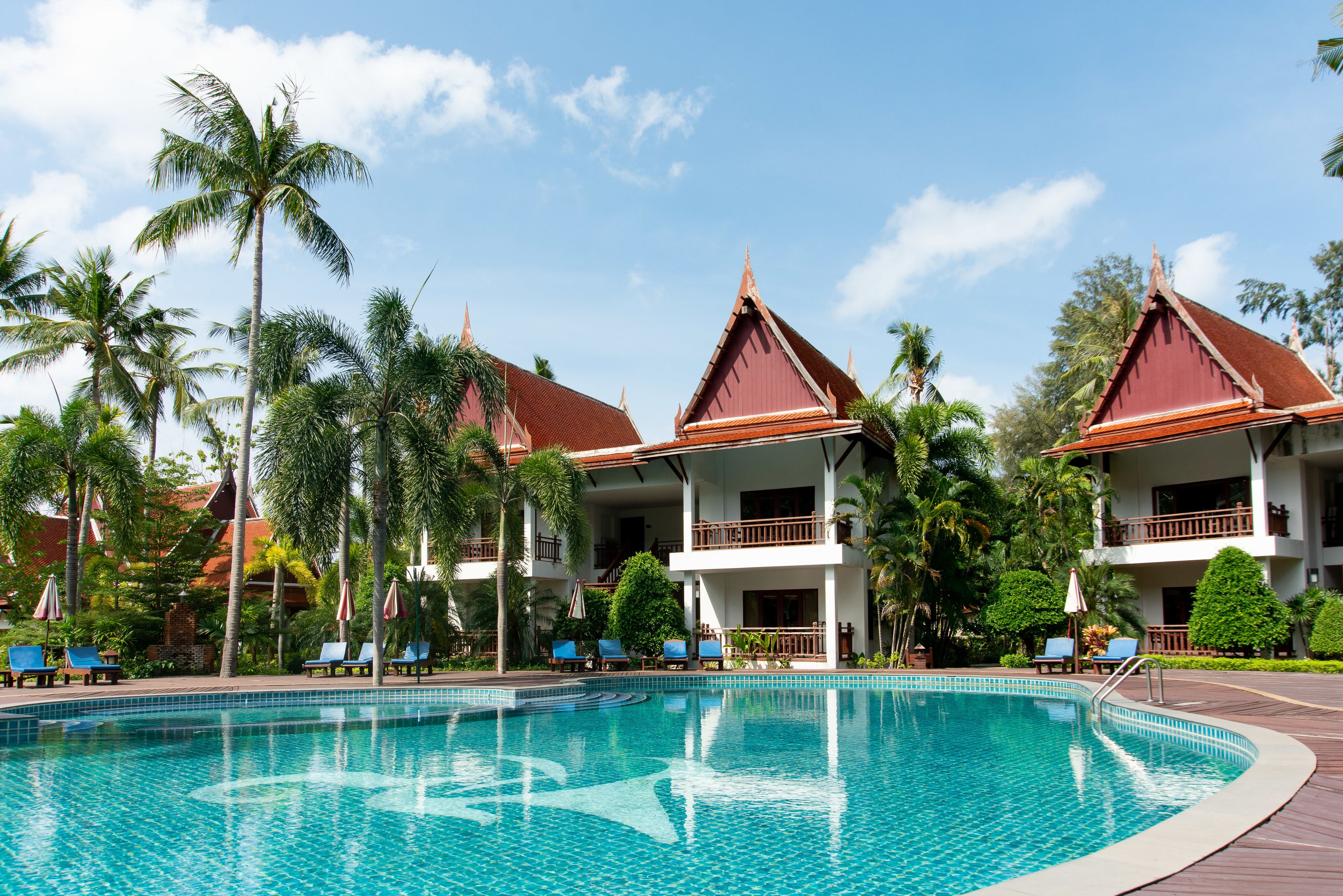 A resort with a swimming pool, palm trees, and traditional architecture.