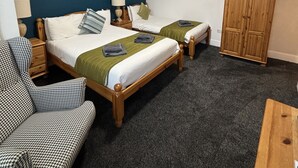 Ett hotellrum med två sängar, en garderob, en stol och ett litet bord.