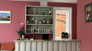 En bardisk med barstolar, hyllor fulla med spritflaskor, en bärbar dator och ett fönster med utsikt.
