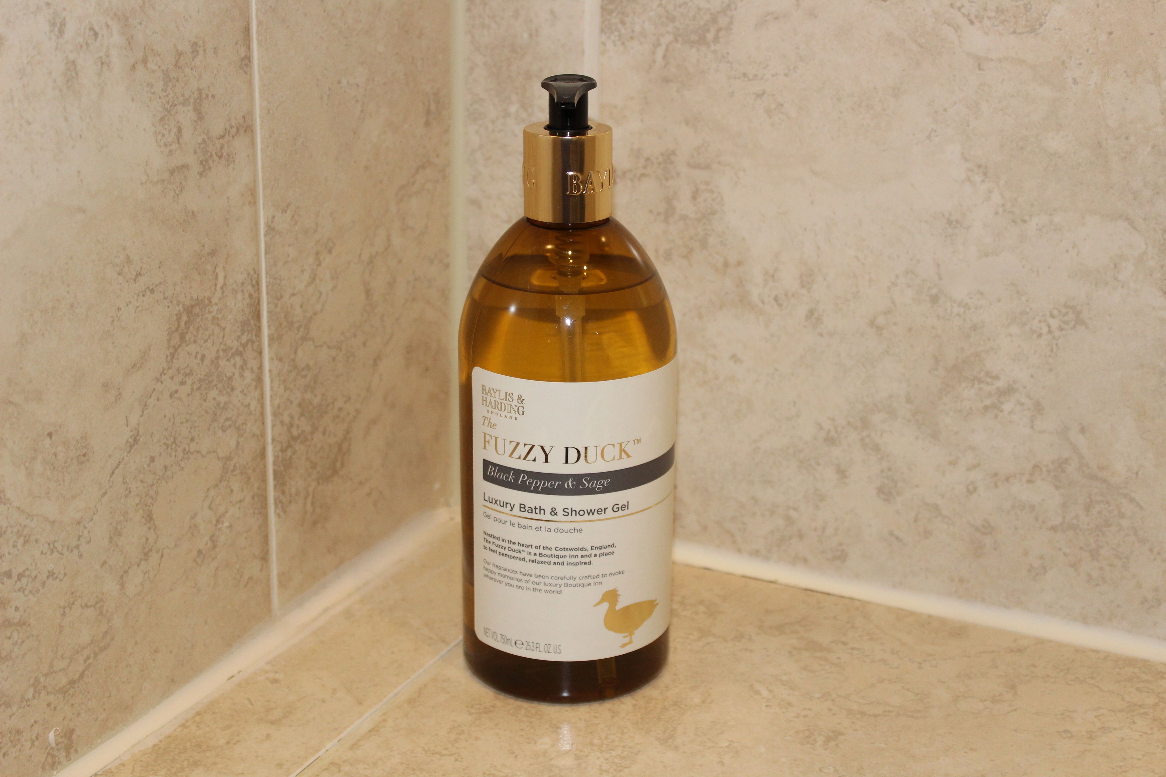 A bottle of Fuzzy Duck Black Pepper & Sage Luxury Bath & Shower Gel on a bathroom counter.