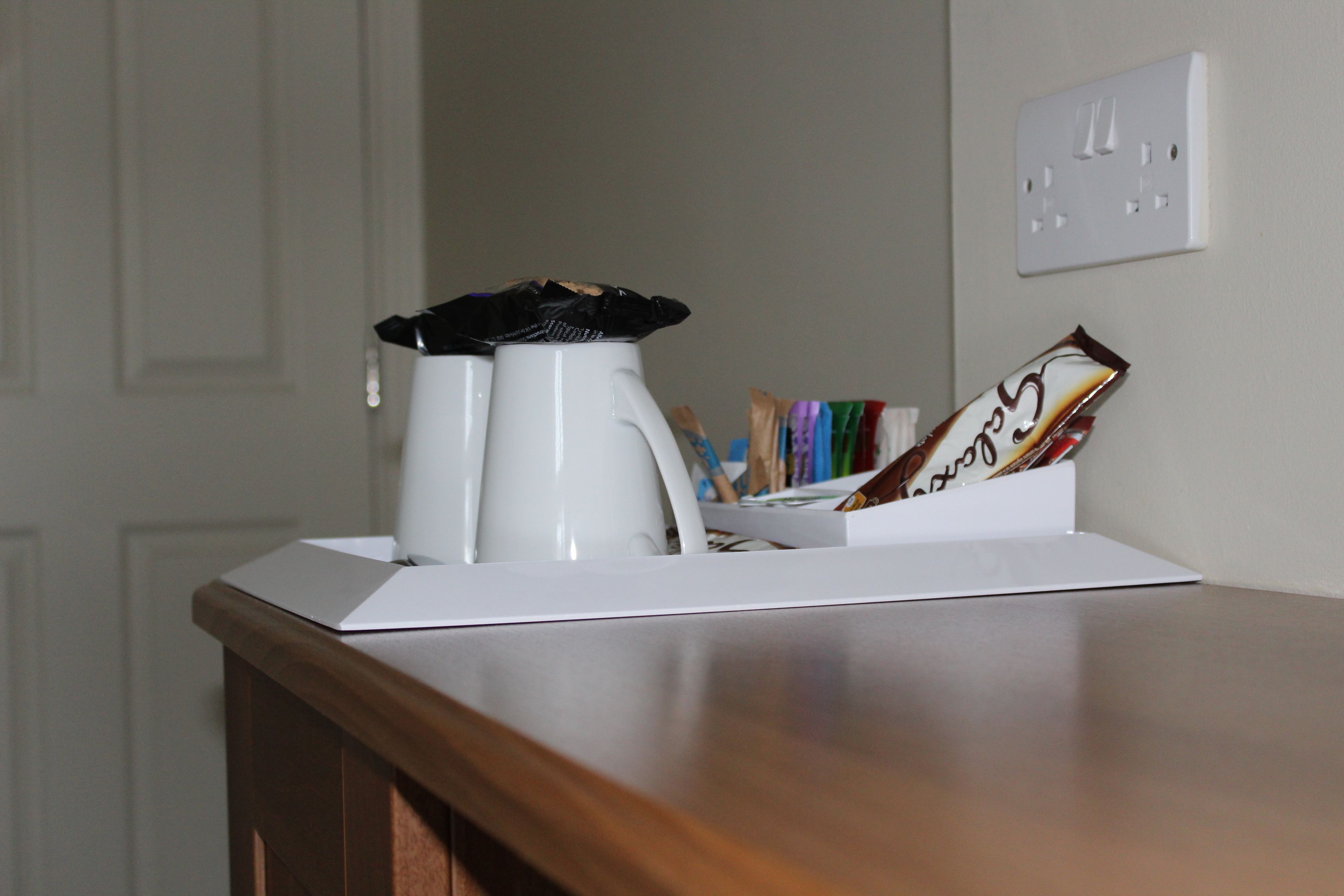 A coffee maker, a mug, and a card holder with cards on a wooden table.