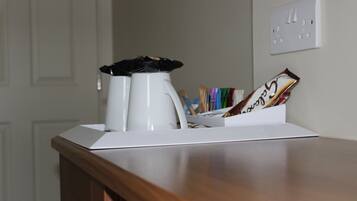 A coffee maker, a mug, and a card holder with cards on a wooden table.