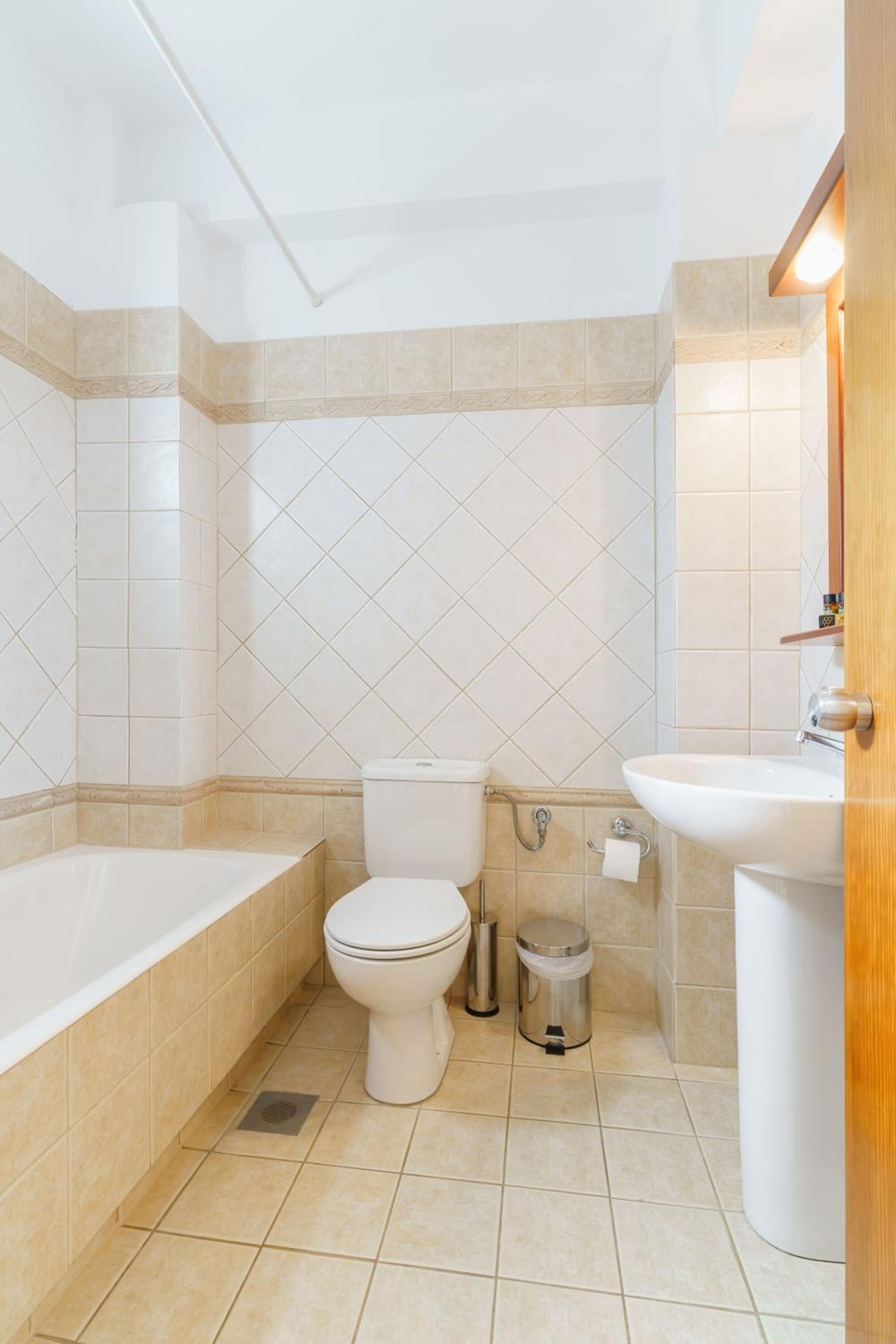 A bathroom with a bathtub, toilet, sink, and trash can.