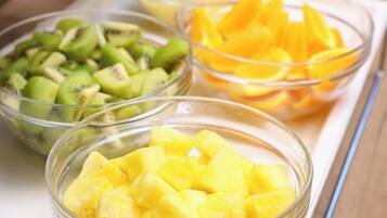 Tres tazones de vidrio con frutas cortadas en cubos: piña, kiwi y mango.