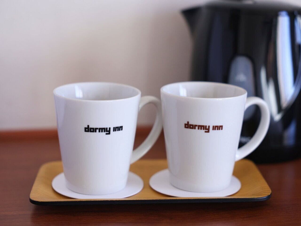 Two white mugs with the text "darmy inn" on a coaster.
