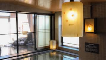 Een modern interieur met een hanglamp, grote ramen en een spiegelende vloer.