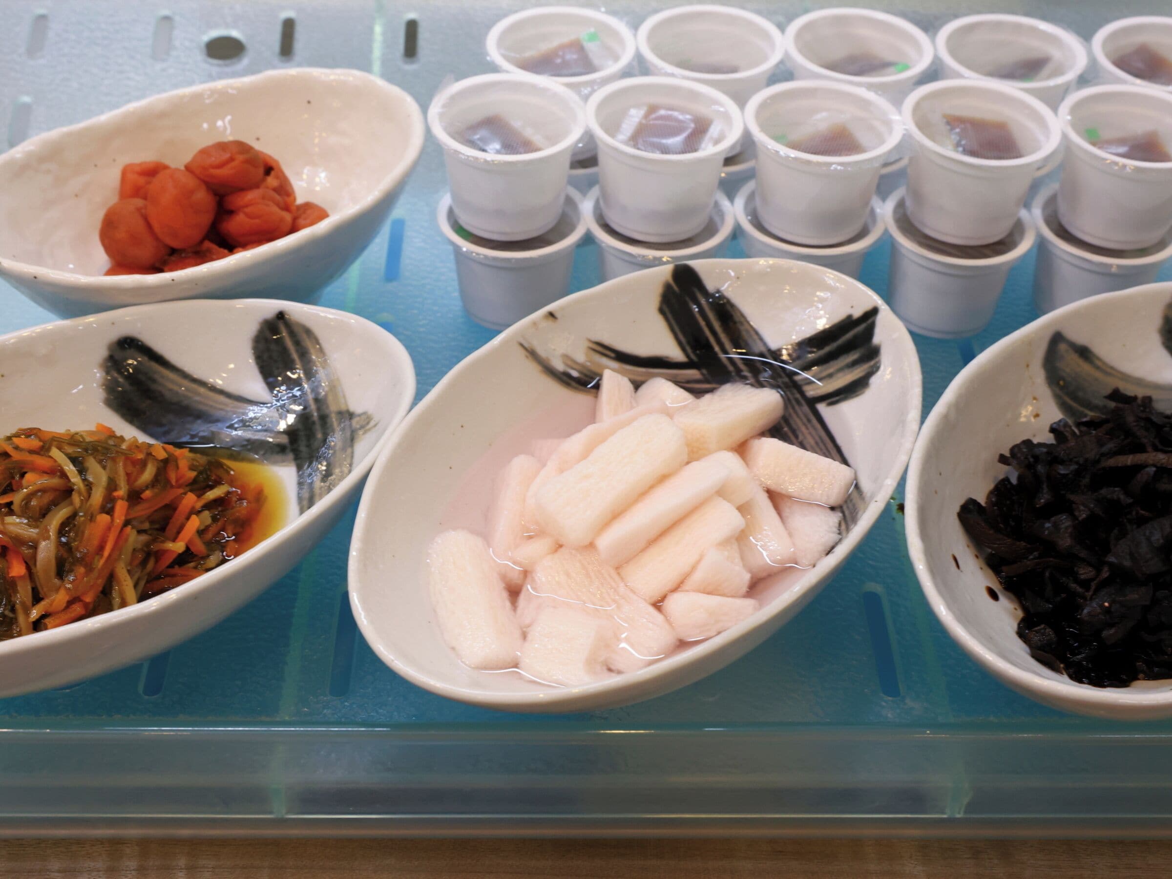 A variety of food items displayed in bowls on a blue surface.