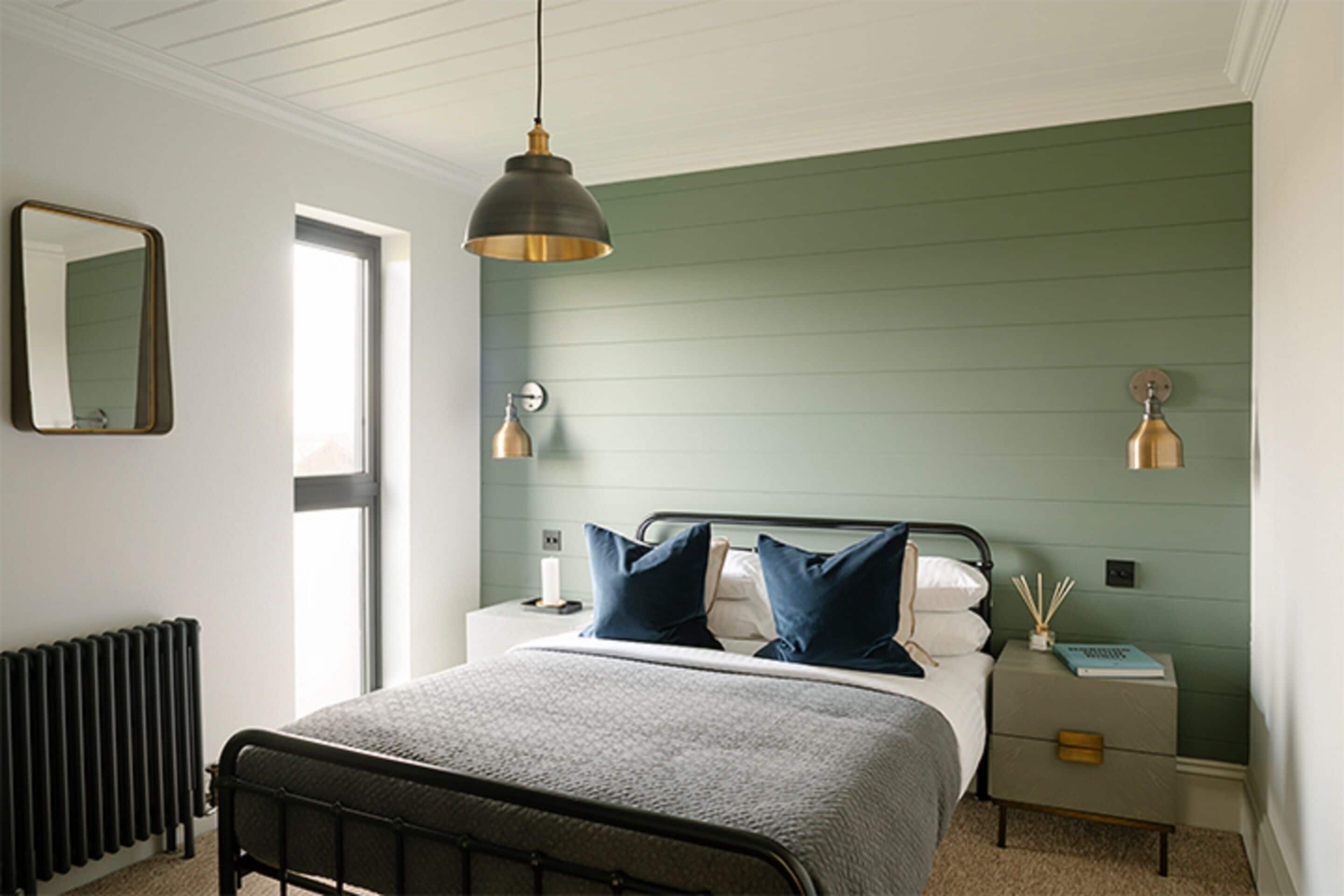 A bedroom with a bed, bedside tables, a mirror, and a radiator.