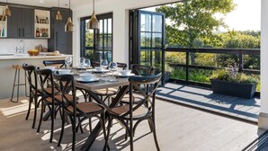 A modern kitchen with dark cabinetry, a central island, and pendant lighting. - Retallack Resort (St. Columb Major)