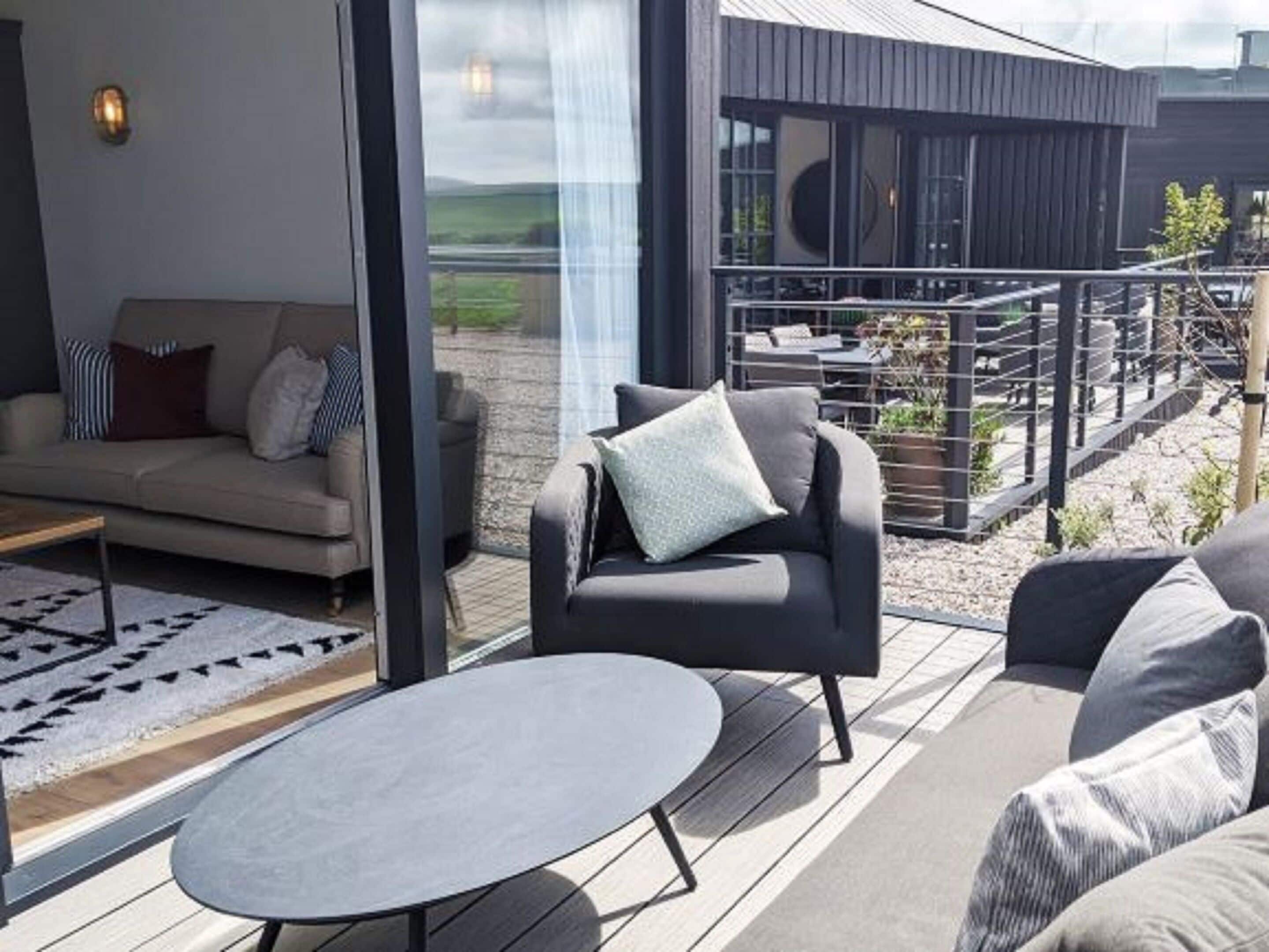 A modern outdoor seating area with a sofa, armchair, and round table.