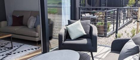 Un área de estar al aire libre moderna con sofá, sillón y mesa redonda.