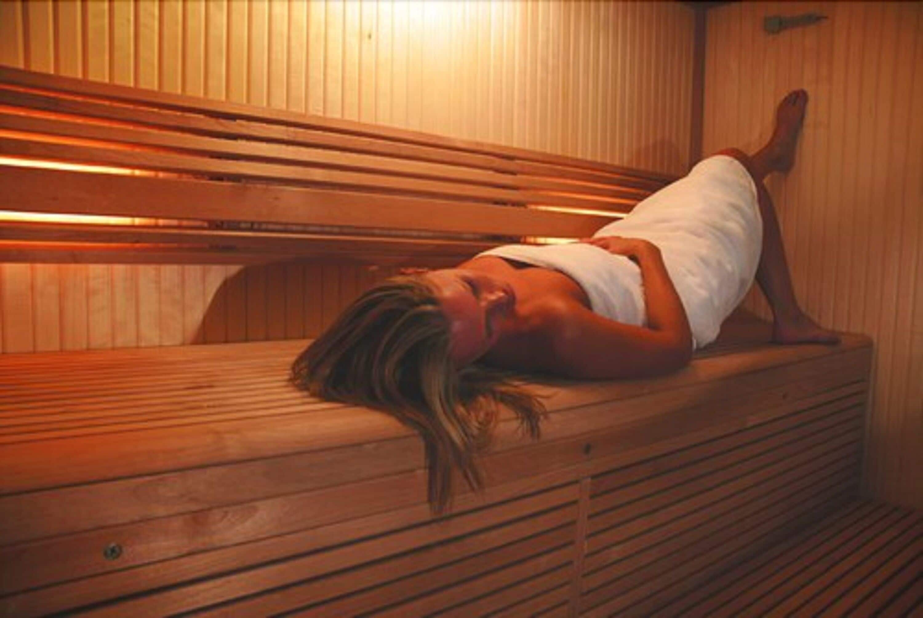 Banco de sauna de madera con una persona acostada.