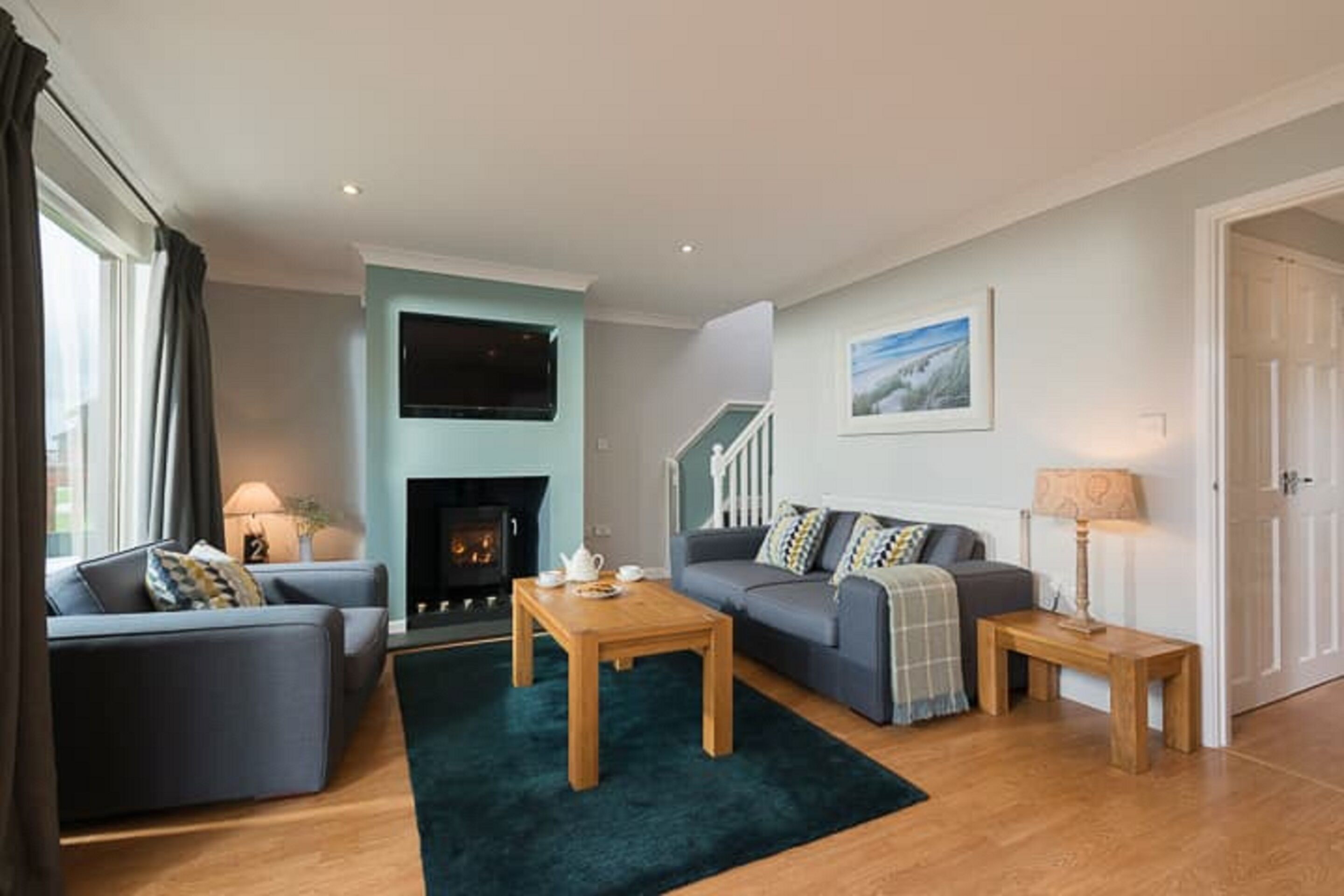 A modern living room with a fireplace, a sofa set, a coffee table, and a staircase leading to an upper floor.