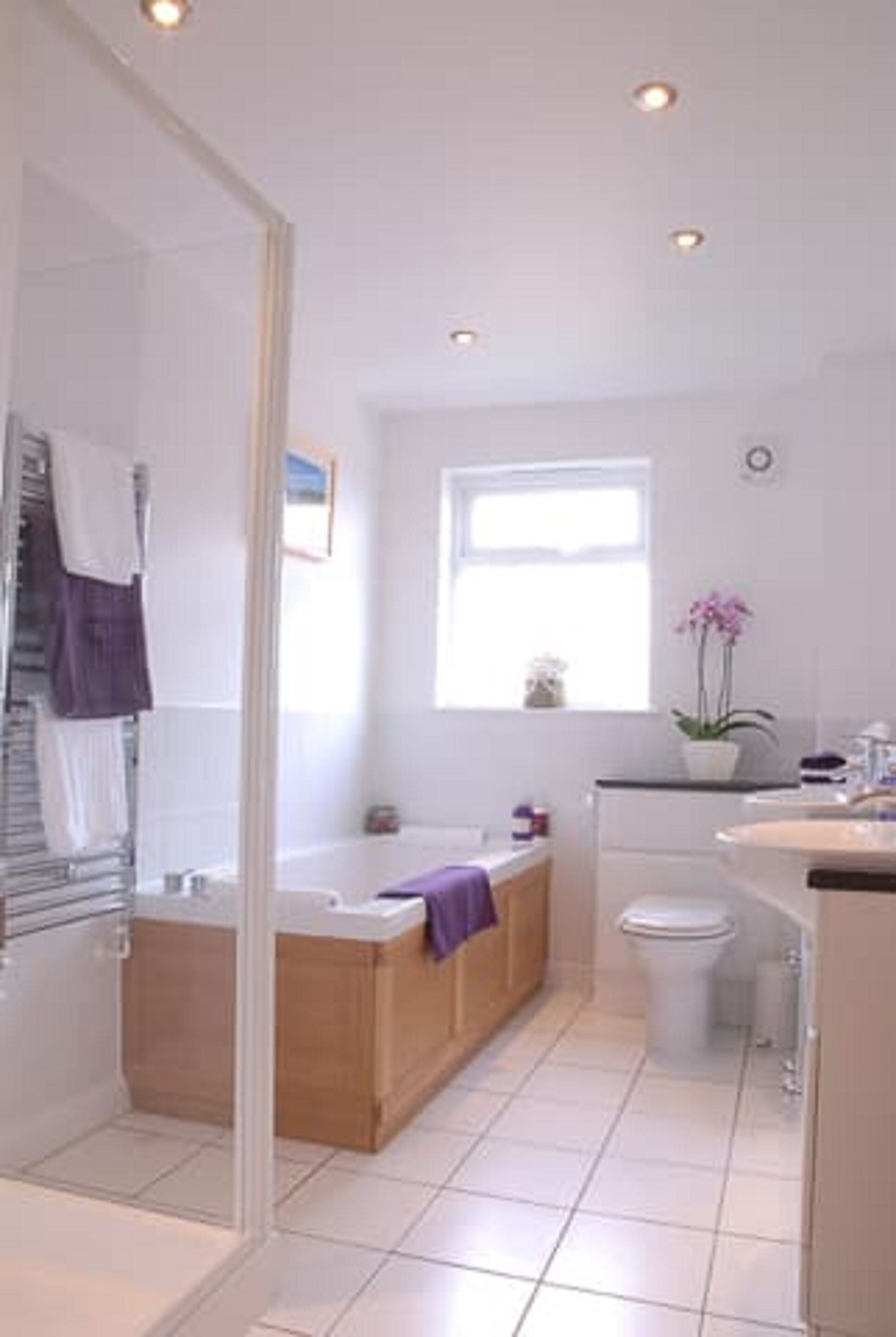 A modern bathroom with a glass shower enclosure, a freestanding bathtub, a toilet, and a sink.