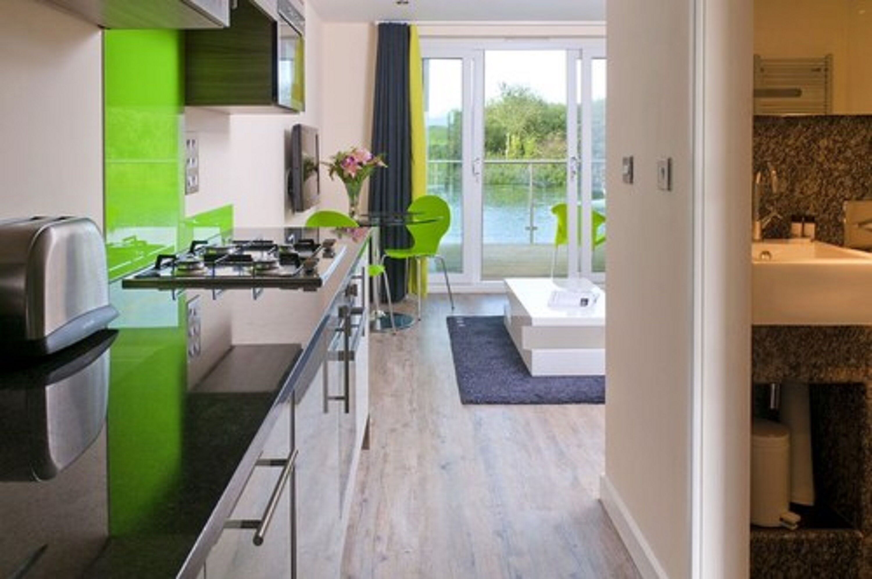 A modern kitchen with a gas stove, a sink, and a dining area with chairs.