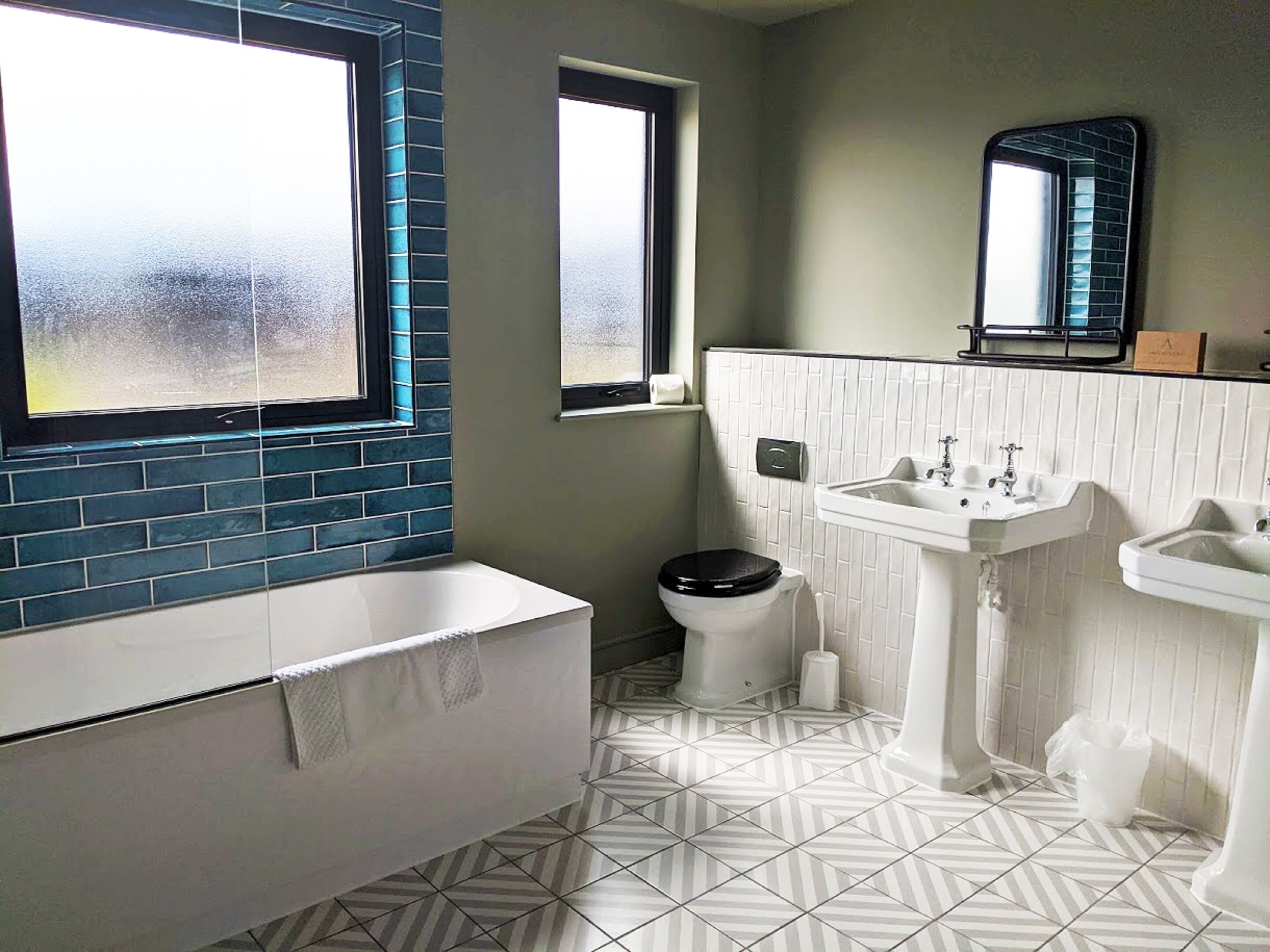 Un baño con bañera, inodoro y dos lavabos.