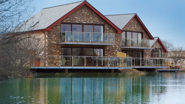 A two-story stone building with a balcony, situated by a body of water. - Retallack Resort (St. Columb Major)
