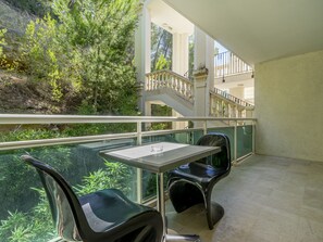 A balcony with a table and chairs, overlooking a garden and a staircase.
