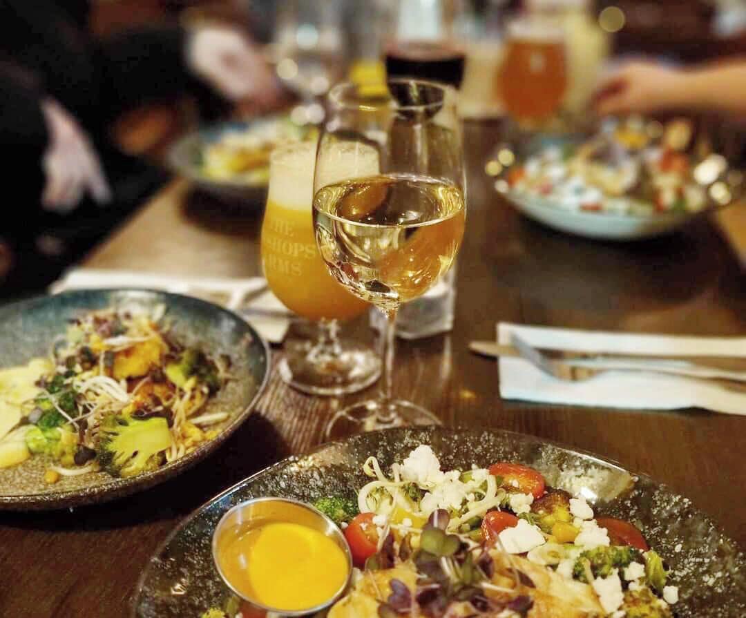 A dining table with plates of food, glasses of wine, and a bottle of wine.