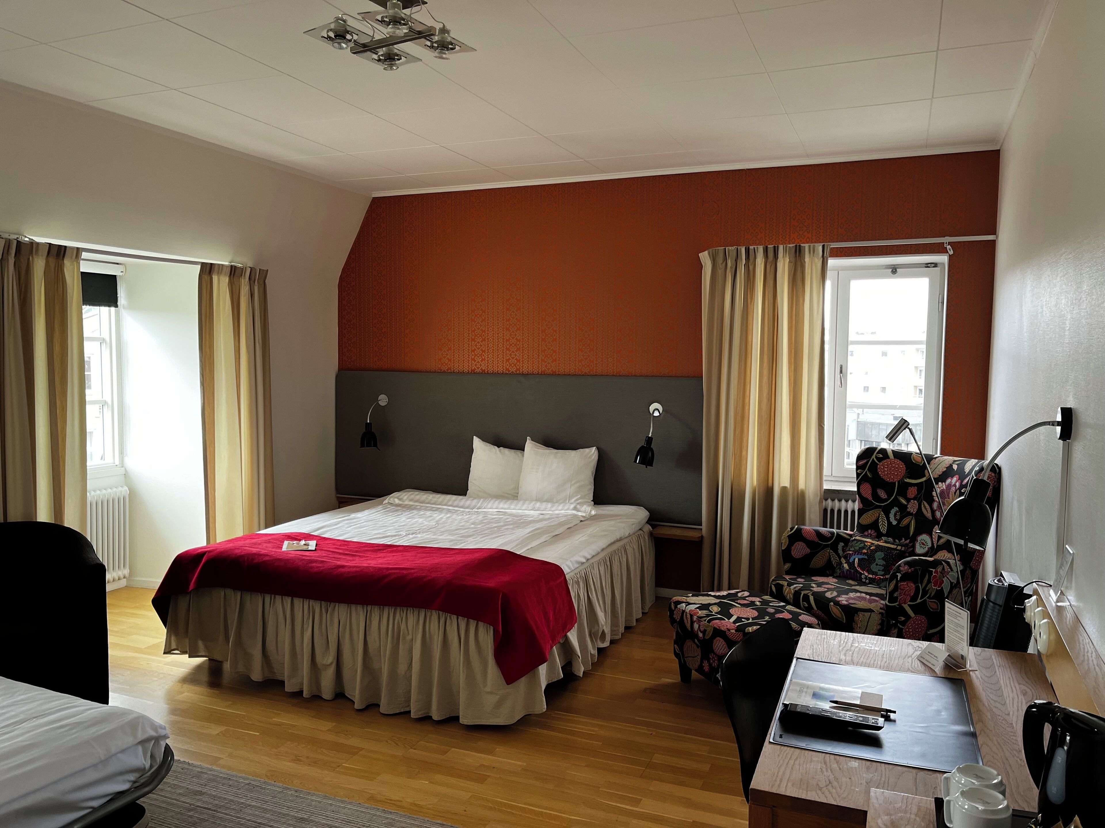 A hotel room with a bed, a desk, a chair, and a window.