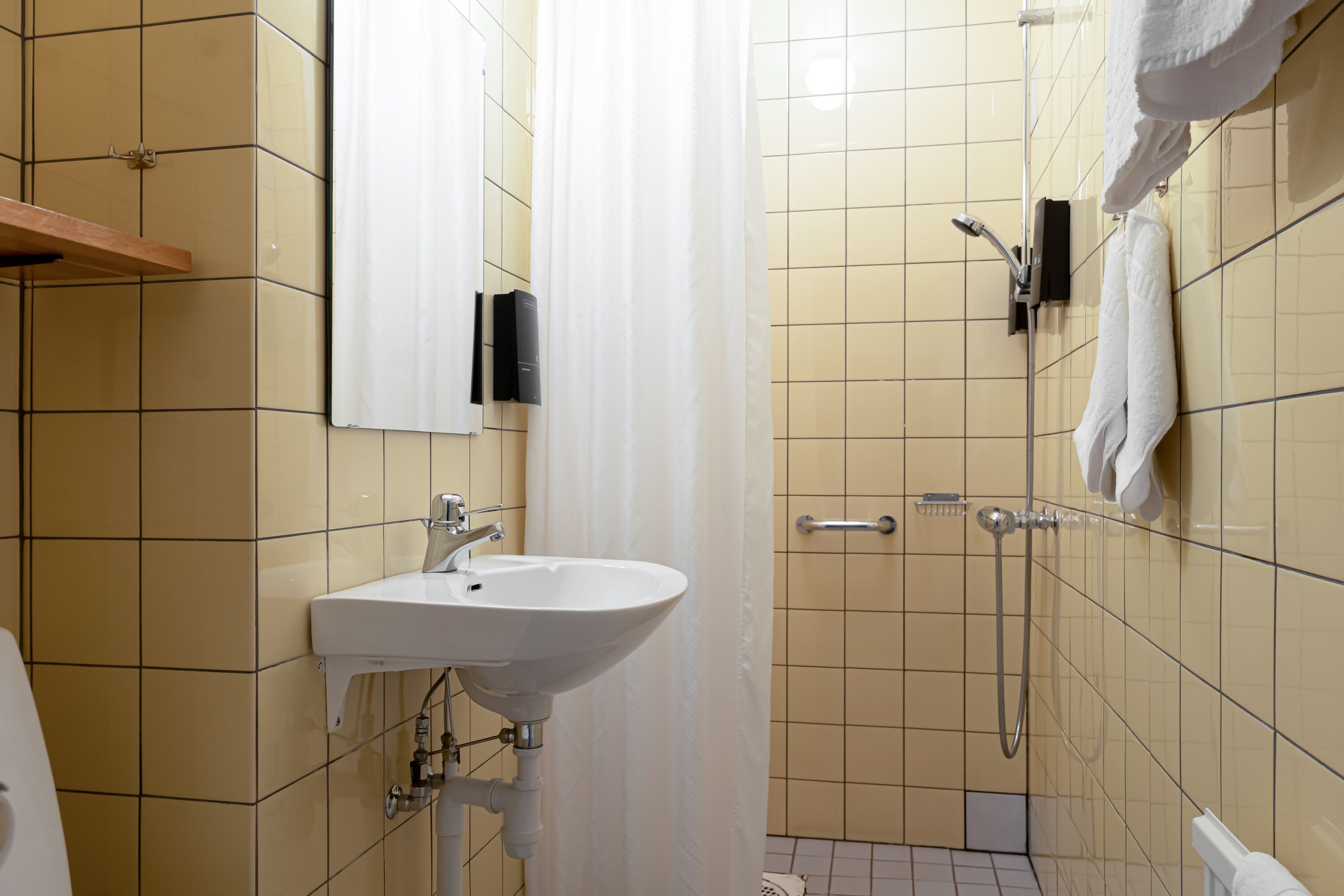A bathroom with a sink, shower, and tiled walls.