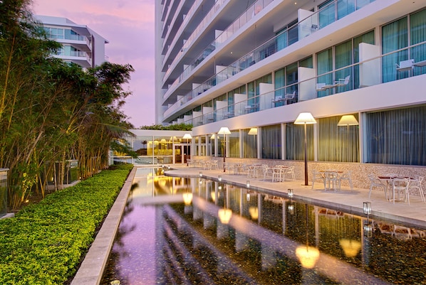 A modern hotel with a pool, outdoor seating, and a well-maintained garden.