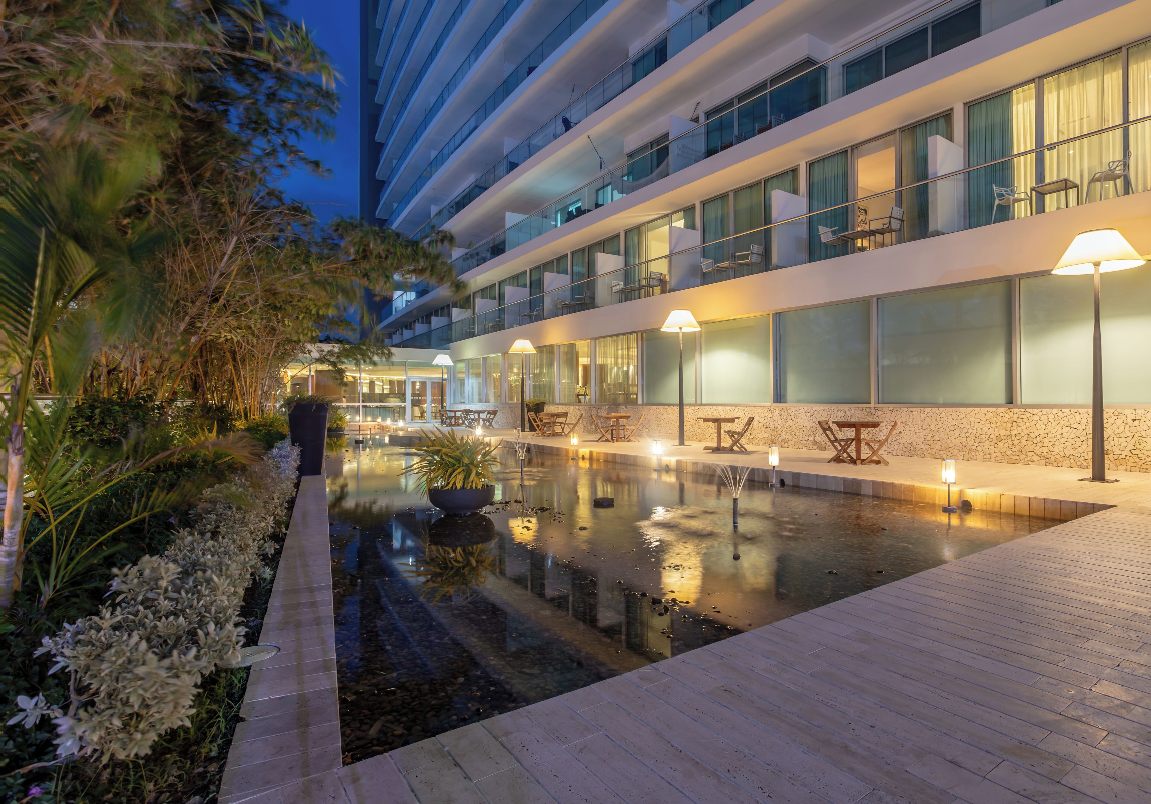 Um hotel moderno com área de piscina, espaço para sentar ao ar livre e varanda bem iluminada.