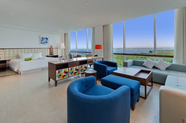 A modern hotel room with a large bed, a desk, a sofa, and a view of the sea. - Holiday Inn Cartagena Morros by IHG (Cartagena)