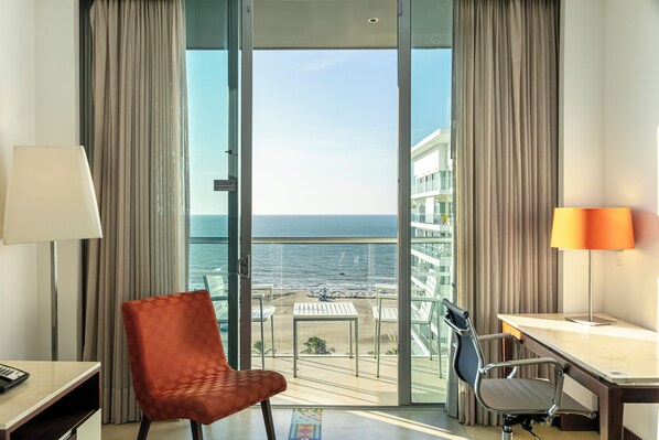 A hotel room with a balcony, a desk, two chairs, and a view of the sea. - Holiday Inn Cartagena Morros by IHG (Cartagena)